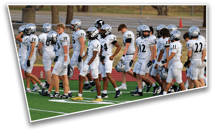 A group of people wearing white football uniforms and helmets are walking together on a green field. Description generated by AI