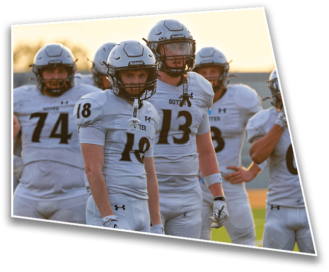 A group of people wearing white football uniforms and helmets stand together outdoors during sunset. Description generated by AI