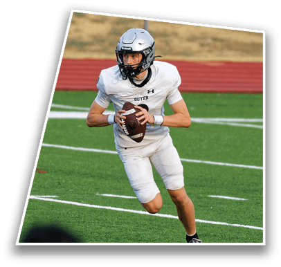 A person wearing a silver helmet and white football uniform is running on a green field while holding a football. Description generated by AI