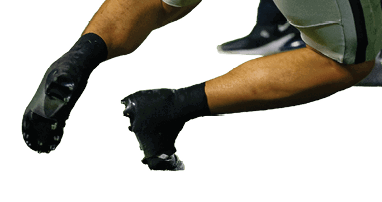 Two football players in white uniforms are being tackled by two players in black uniforms on a green field during a game. Description generated by AI