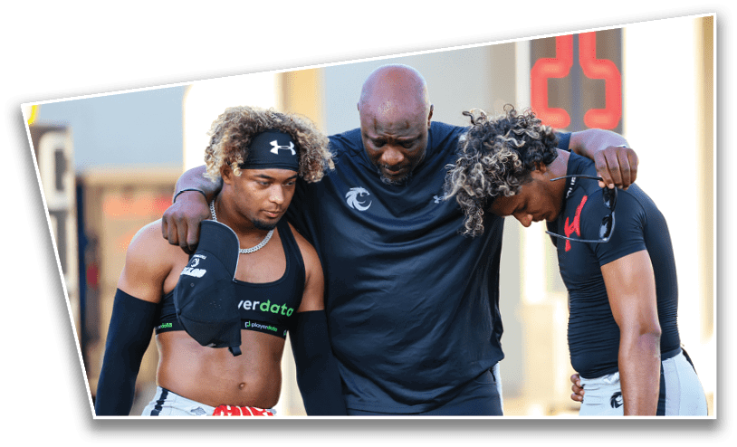 Three people with athletic clothing stand closely together with their heads bowed and arms around each other in a moment of support or reflection. Description generated by AI