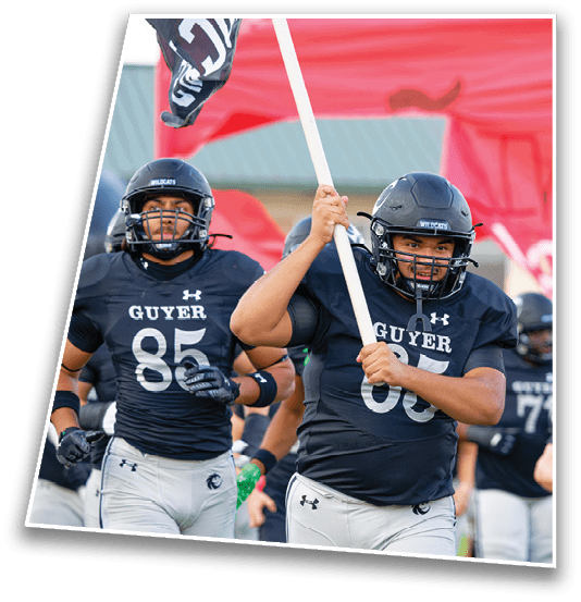 A person in a football uniform and helmet is holding a flag pole while running with teammates in similar uniforms behind them. Description generated by AI