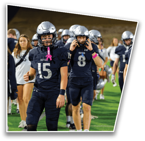 People in football uniforms and helmets are walking on a field with some people in casual clothing in the background. Description generated by AI