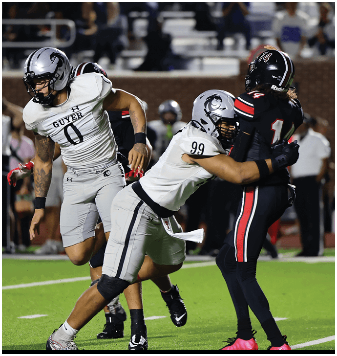 A person in a white football uniform is tackling another person in a black football uniform during a game on a green field. Description generated by AI