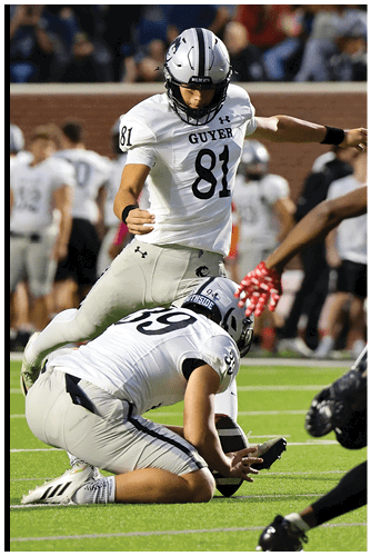 A sports helmet with a wildcat logo is visible at the bottom of the image with a blurred crowd of people in the background. Description generated by AI