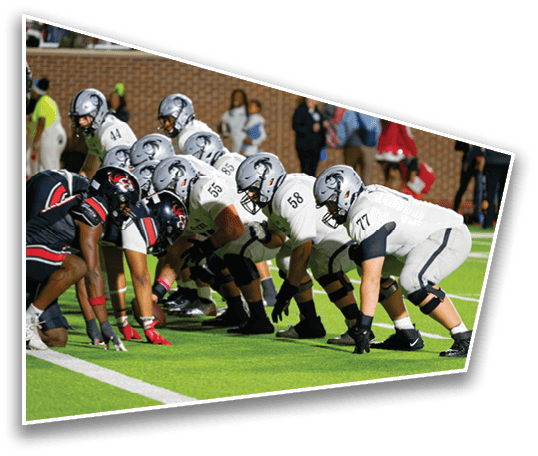 Two opposing American football teams are lined up facing each other on the field, ready for the next play. Description generated by AI
