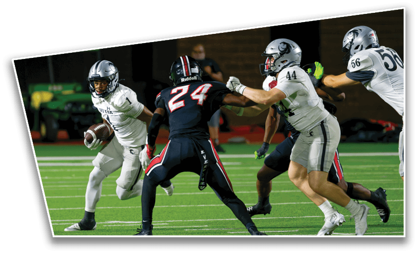 People playing American football on a field with one person running with the ball while others attempt to block or tackle. Description generated by AI