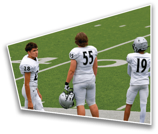 Two people in white football uniforms with numbers 28 and 55 stand on a green football field. Description generated by AI