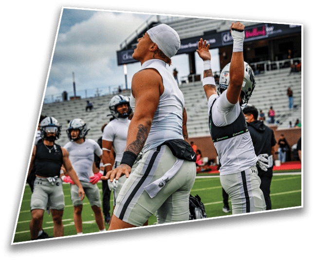 People in athletic gear are celebrating on a football field with empty stadium seats in the background under a cloudy sky. Description generated by AI
