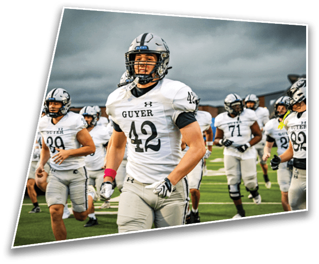 Adults in football uniforms are running on a green field during a game or practice. Description generated by AI