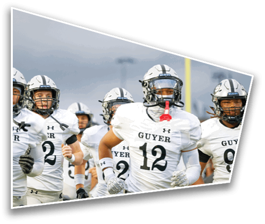 A group of people wearing white football uniforms and helmets with the word Guyer on the jerseys are walking together on a field. Description generated by AI