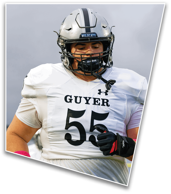 A person wearing a white football uniform with the number 55 and a silver helmet is on a field, appearing focused and ready for action. Description generated by AI