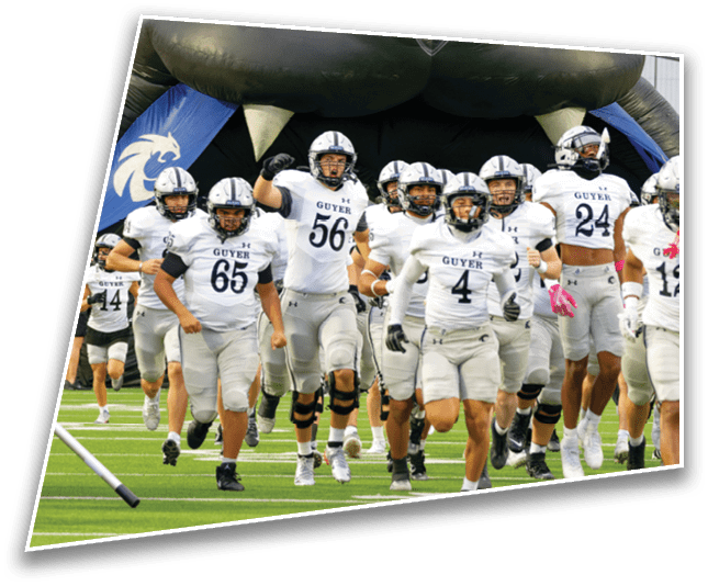 A group of football players in white and gray uniforms with helmets are running energetically onto a field. Description generated by AI