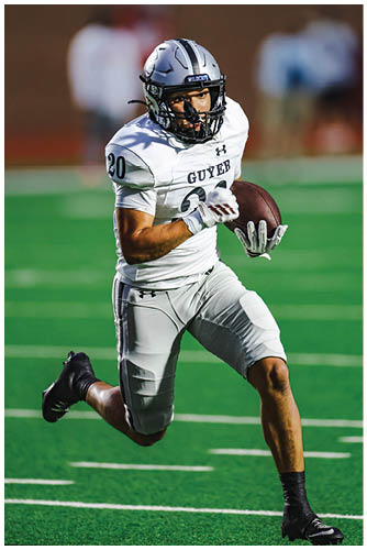 A person wearing a football uniform with the number 20 is running on a field while holding a football. Description generated by AI