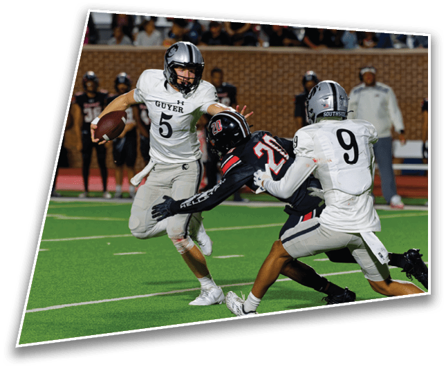 Three football players in action on a field with two players in white uniforms attempting to tackle a player in a black uniform. Description generated by AI