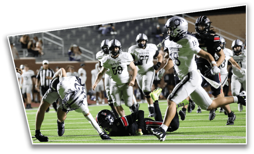 Players in football uniforms are actively engaged in a game on a field with spectators in the background. Description generated by AI