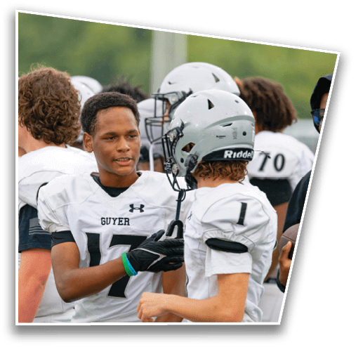 A group of people wearing white football uniforms and helmets are gathered together, with one person in the center shaking hands with another. Description generated by AI