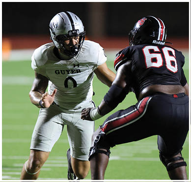 Two football players in action on a field at night, one wearing a white uniform with the number zero and the other in a black uniform with the number sixty-eight. Description generated by AI