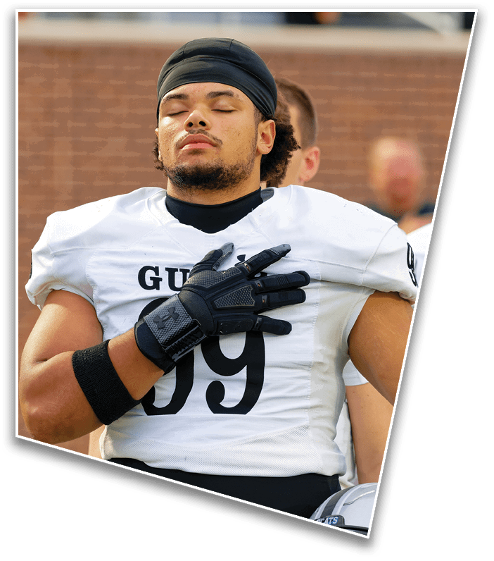 A person with curly hair wearing a black head covering and white sports uniform has their eyes closed and appears to be resting or meditating. Description generated by AI