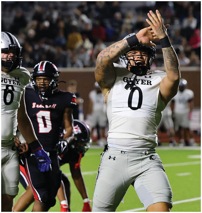 A person in a white football uniform with the number zero is celebrating with hands raised while another person in a black football uniform with the number zero stands nearby on a football field. Description generated by AI
