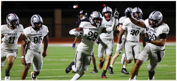 Several people in white football uniforms are actively running on a green field during a game. Description generated by AI