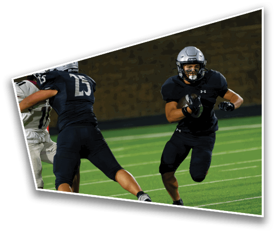 A person wearing a black football uniform and silver helmet is running on a green field while holding a football. Description generated by AI