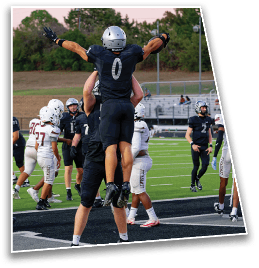 People wearing football uniforms are on a field with some players in black celebrating while others in white stand nearby. Description generated by AI