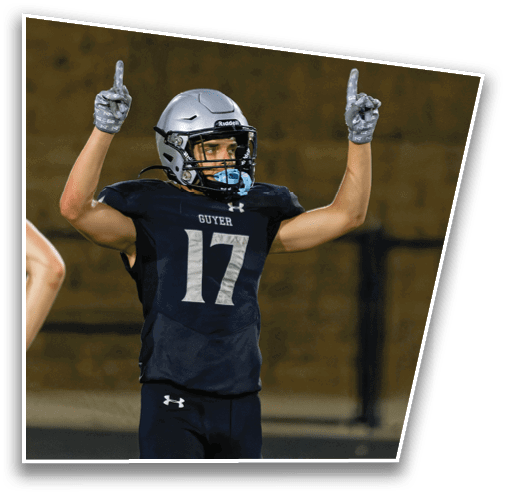 A person wearing a football uniform with the number 17 and the name Guyer on the jersey is raising both arms with index fingers pointing upward on a sports field. Description generated by AI