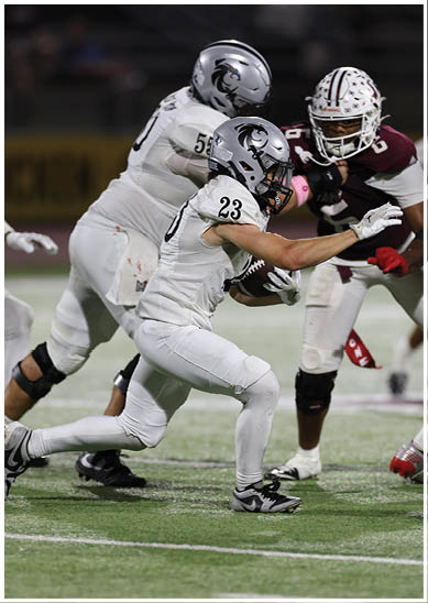 A person in white football gear with the number 23 is running with the ball while being pursued by other players on a football field. Description generated by AI