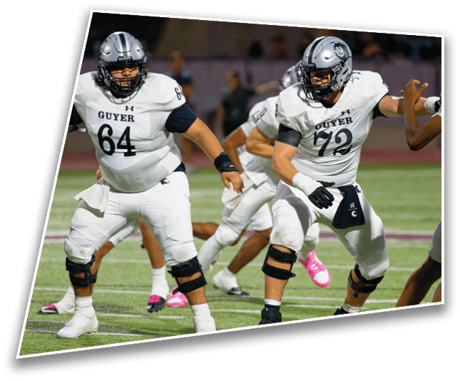 Two people in football uniforms with helmets and knee braces are positioned on a field, appearing ready to engage in a play during a game. Description generated by AI