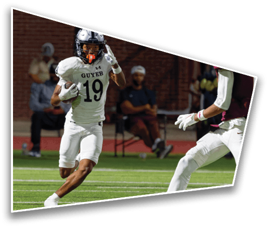 A person wearing a white football uniform with the number 19 is running on a field while holding a football, with another player reaching out toward them. Description generated by AI
