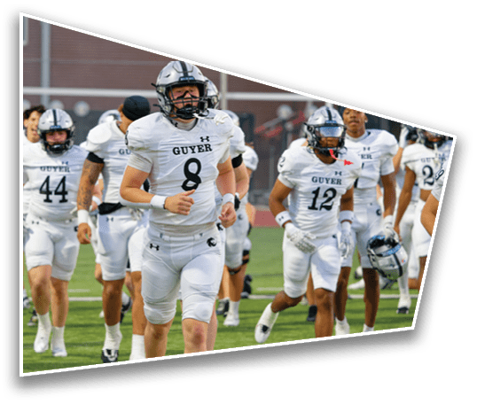 A group of people in white football uniforms with helmets are running on a field, appearing to enter or warm up for a game. Description generated by AI