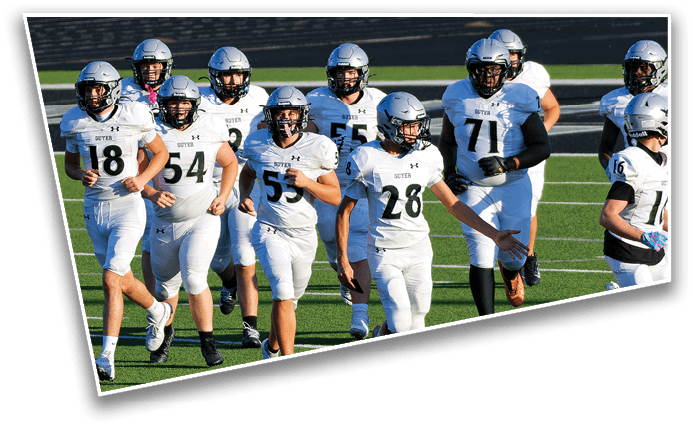 A group of people wearing white football uniforms and helmets are walking together on a green field. Description generated by AI