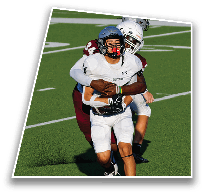 Two people wearing football helmets and uniforms are engaged in a play on a green football field. Description generated by AI