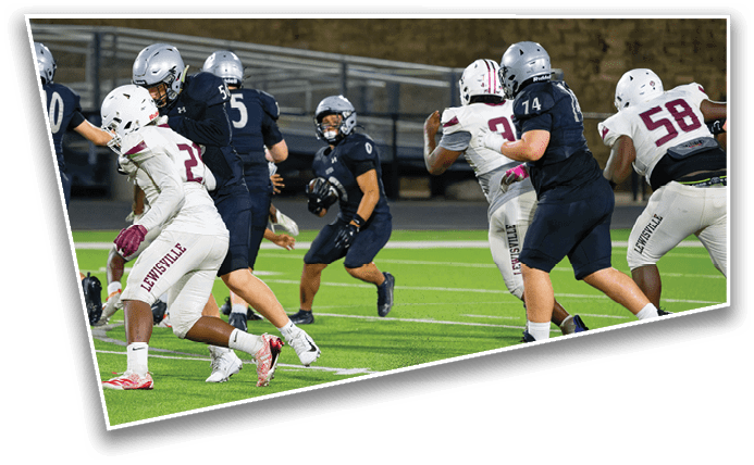 People in football uniforms are actively engaged in a game on a green field under stadium lights. Description generated by AI