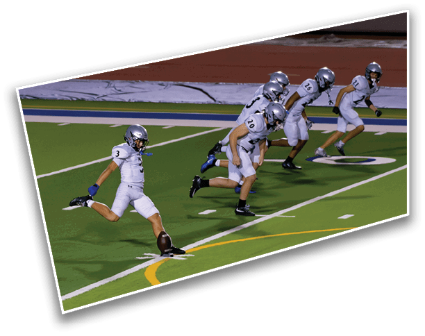 A group of people in football uniforms are lined up on a field with one person kicking a football. Description generated by AI