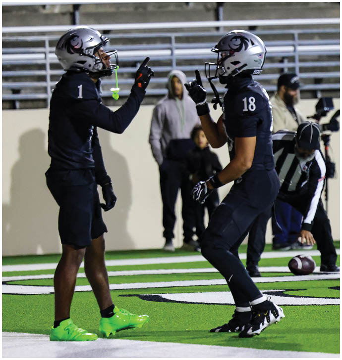 A person in a white football uniform is tackling another person in a black football uniform during a game on a green field. Description generated by AI