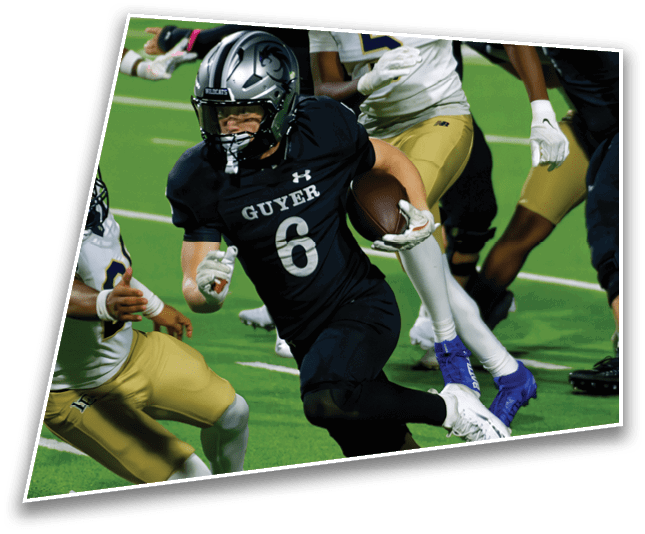 A person wearing a black football uniform with the number six is running with the ball while other players in gold and white uniforms attempt to tackle them on a green field. Description generated by AI
