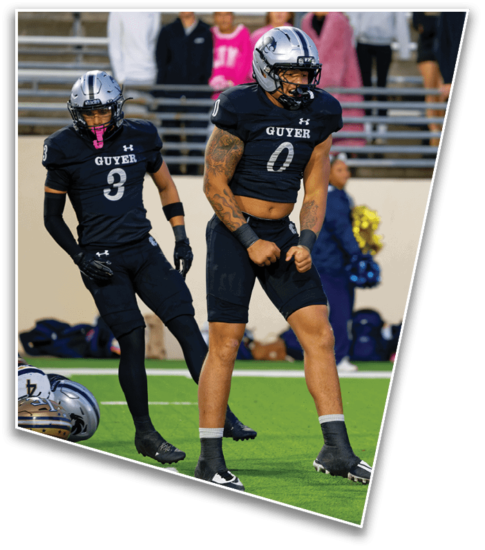 A person wearing a black sports uniform with the number six is sitting on the field while other players and a referee stand nearby during a football game. Description generated by AI