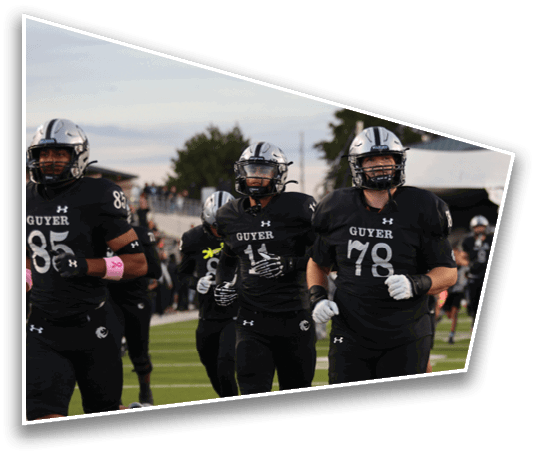 People wearing black sports uniforms are running on a green field during a game or practice. Description generated by AI