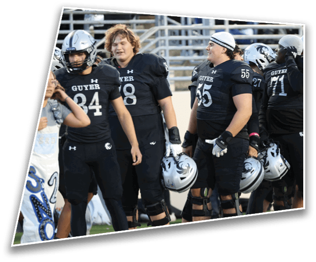 A group of people wearing black football uniforms and holding helmets stand on a field. Description generated by AI