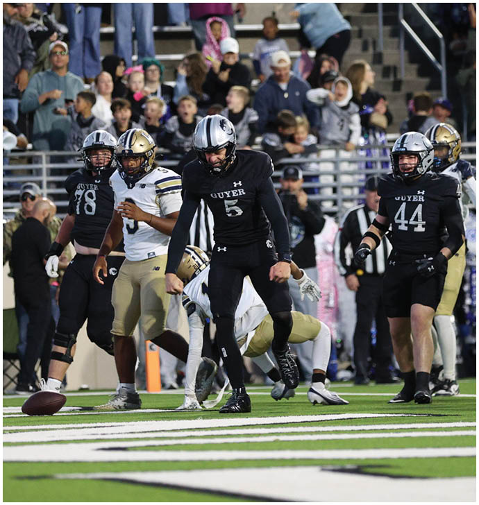 People wearing sports uniforms and cleats are on a football field with a football on the ground near the center. Description generated by AI