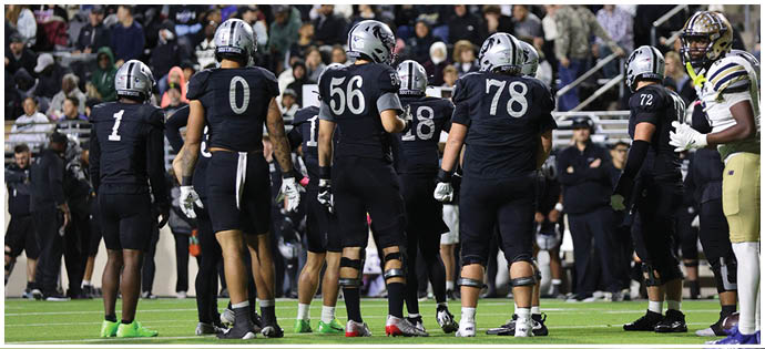 A crowd of people is seated in stadium bleachers behind a banner that reads “GUYER WILDCATS." Description generated by AI