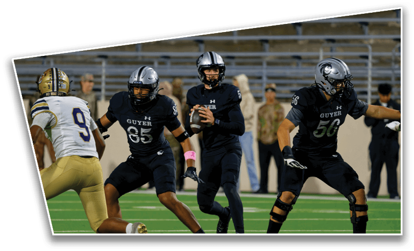 Three people in black football uniforms with helmets are on a football field, with one person holding a football and preparing to throw it while the others appear to be blocking opponents. Description generated by AI