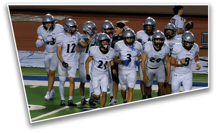A group of people wearing football uniforms and helmets are walking together on a field, appearing focused and ready for a game. Description generated by AI