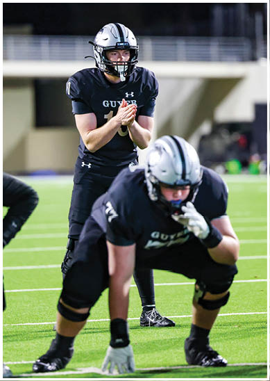 People in football uniforms are positioned on a field preparing for a play during a game. Description generated by AI