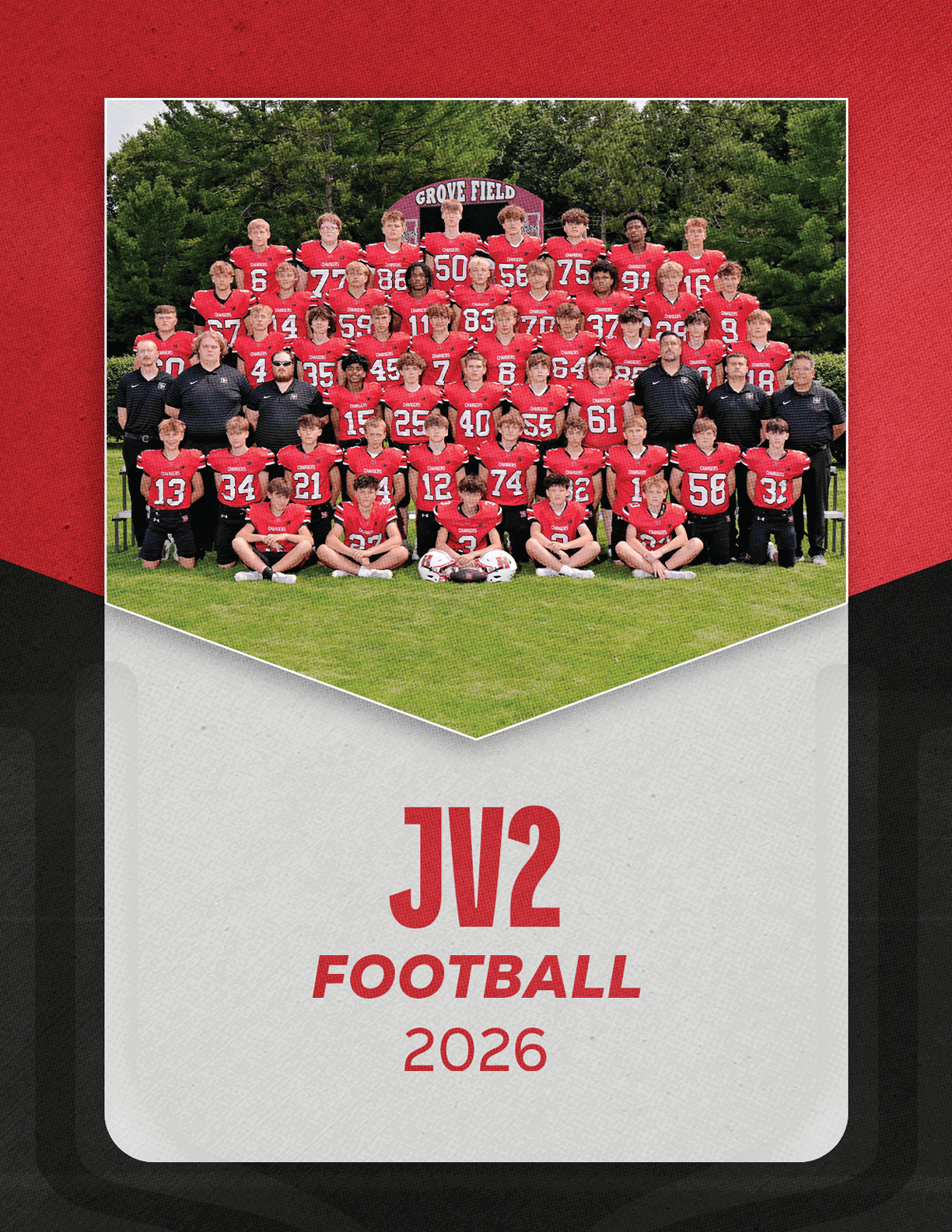 A large group of people wearing red and black football uniforms pose together on a grassy field with trees in the background and a sign that reads “JV2 Football 2026" below the photo. Description generated by AI