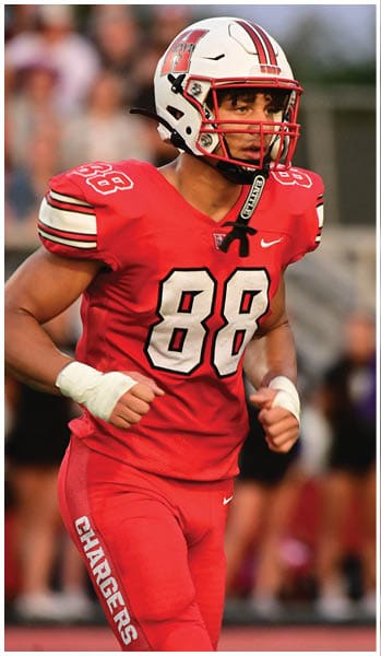 A person wearing a red football uniform with the number 88 and a white helmet is running on a field. Description generated by AI