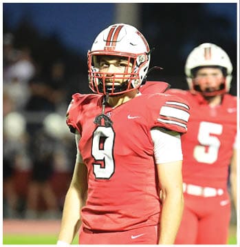 A person wearing a white and red sports helmet is visible at the bottom of the image against a dark blue sky background. Description generated by AI