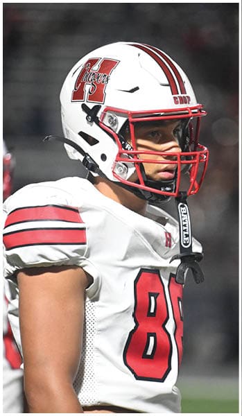 A person wearing a white football helmet with red stripes and a large red “H" logo with the word "Chargers" on the side is looking intently forward. Description generated by AI